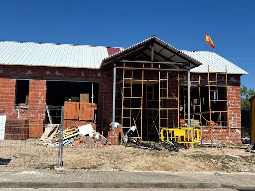 Obra de construcción residencial moderna con estructura de ladrillo y acero bajo un cielo azul